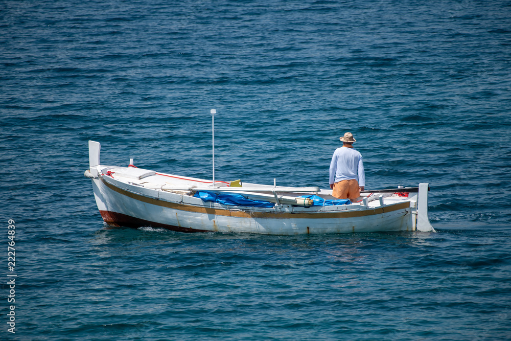 Fisherman in traditional wooden boat at sea