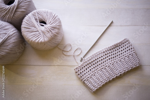 Handmade crochet tiny hat from grey cotton yarn, hobby crafts crocheting with steel hook, wooden background