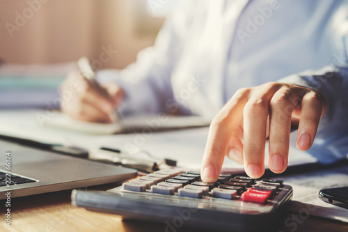 business man working in office and using calculator with pen
