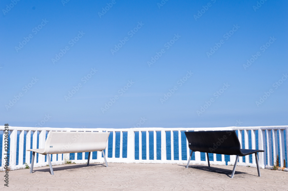 Pair of black and white benches overlooking the Cantabrian Sea in the village of Candas, Asturias, Spain.