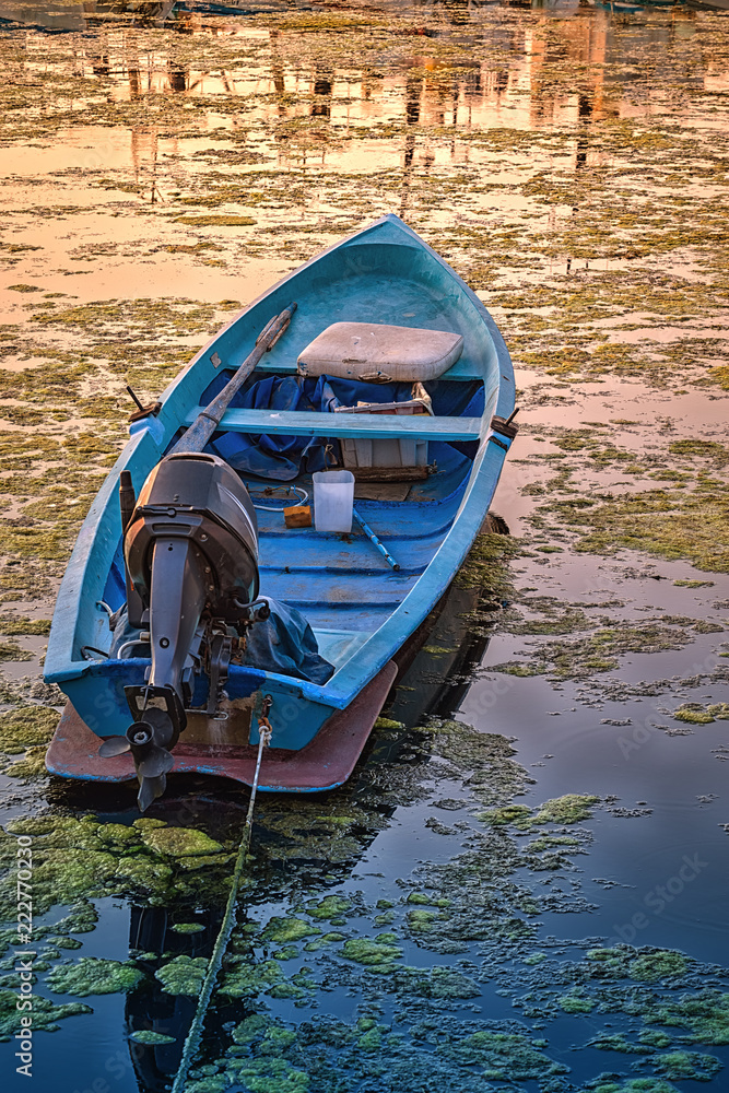 Small fishing boat alone in the water on sunset.Motor boat floating on the  calm water of the harbour of Sozopol, Bulgaria Stock Photo