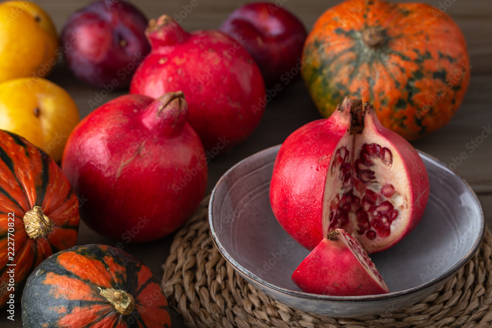 Pomegranates, gourds and plums on a kitchen table Pomegranates, gourds and plums on a kitchen table