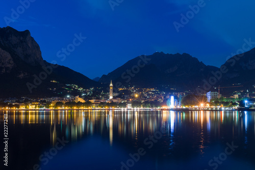 Night view of Lecco reflected on Lake Como with the mountains in the background
