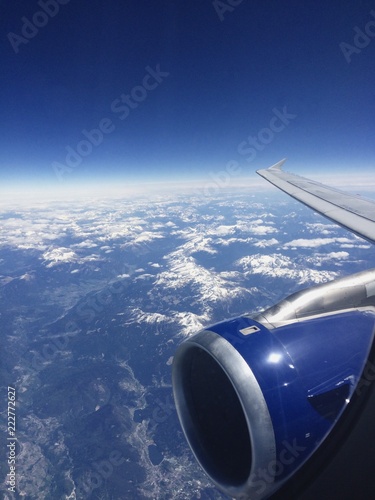 View from above of the Italian Alps from an airplane window on a clear day with a blue sky.