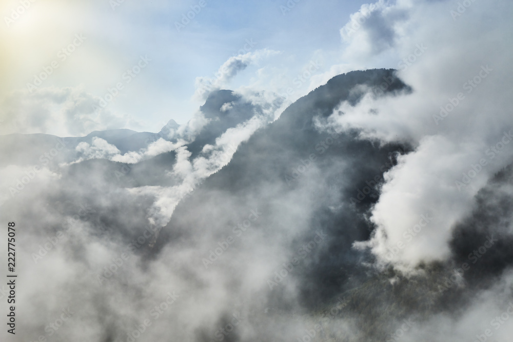 Obraz premium Scenic view of misty mountains above Halstatt village in Austria.