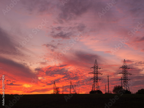 dramatic orange hot summer sunset sky with electric lines towers