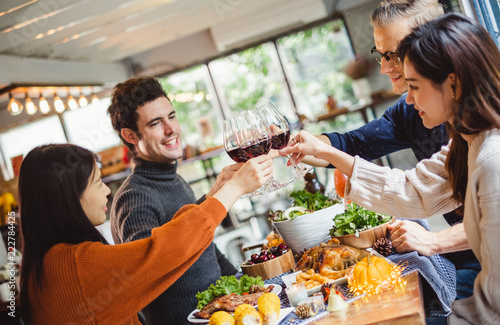 Group of young people celebrating Christmas party dinner with clinking glass of wine