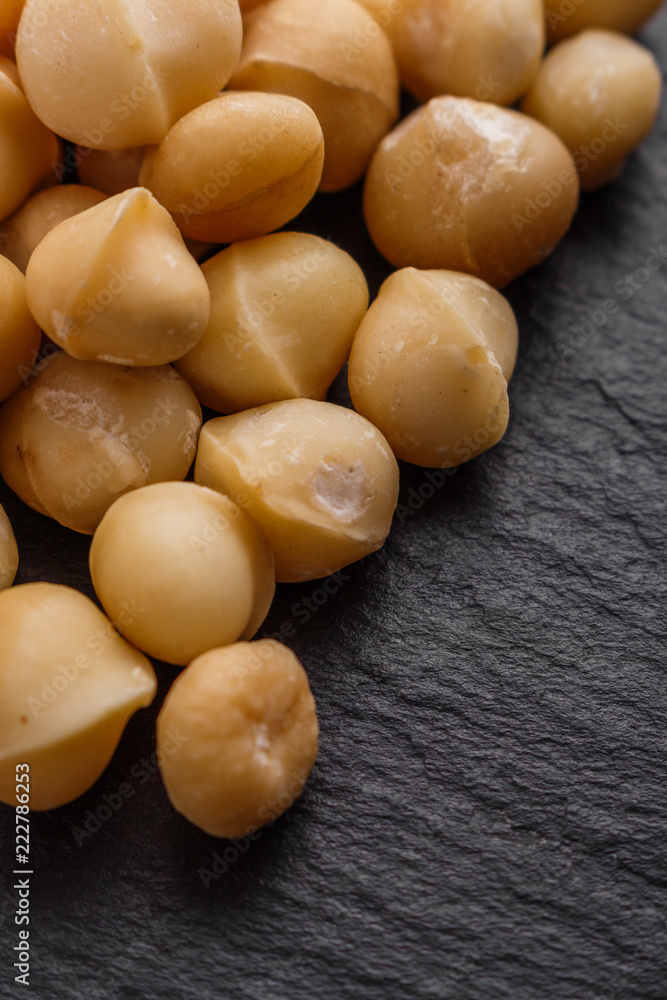 delicious macadamia nuts on a dark stone background delicious macadamia nuts on a dark stone background
