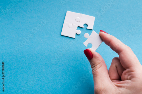 Hand putting last piece of puzzle on blue background photo