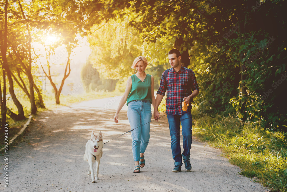 Dog with owners spend a day at the park. Young couple and husky running, playing and having fun. Dog with owners spend a day at the park. Young couple and husky running, playing and having fun.