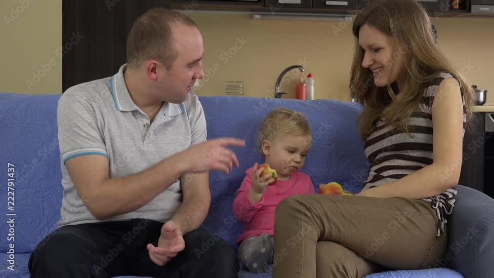 family with little baby eat red fresh apple sit on sofa. 4K family with little baby eat red fresh apple sit on sofa. 4K