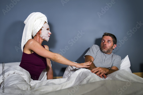 funny lifestyle portrait of man and woman featuring weird married couple with wife in head towel and makeup face mask demanding sex to scared and reluctant husband