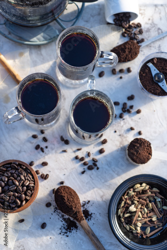 above view of mugs of hot black coffee still life with whole coffee beans, ground coffee, coffee grinder © mariekazalia