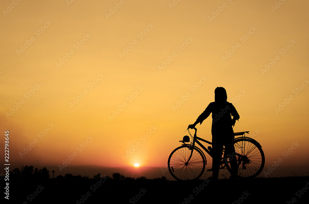 Obraz premium Silhouette woman with bicycle, walking, sunset background