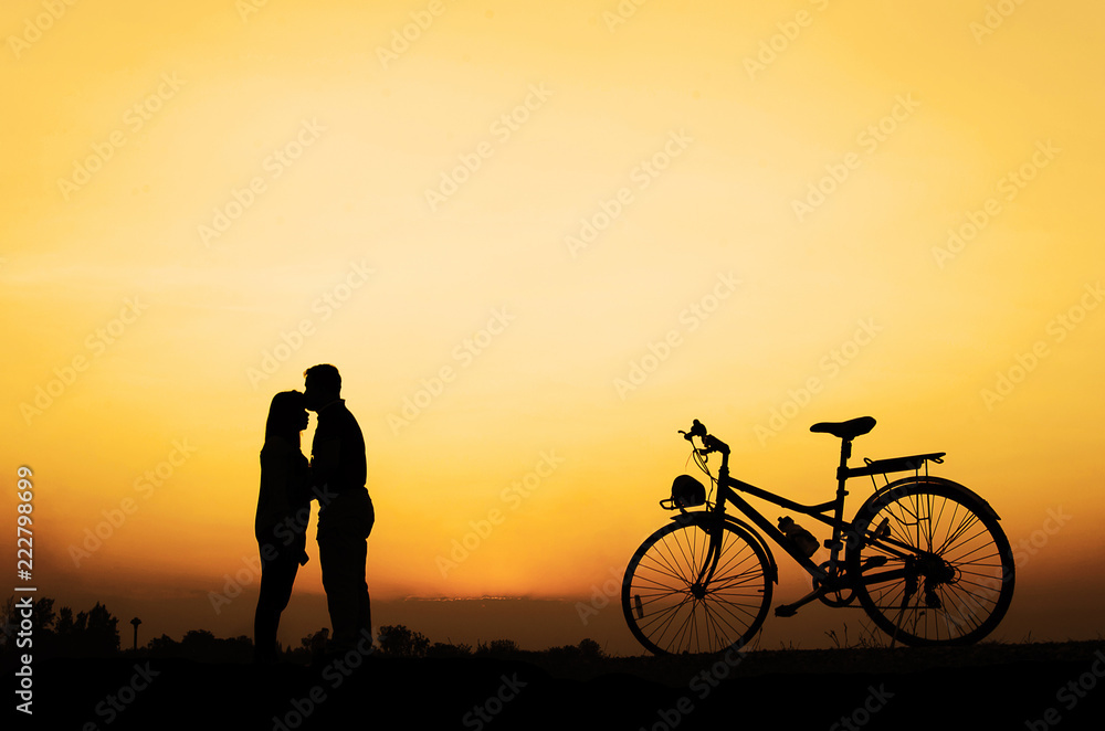 Silhouette of sweet couple in love happy time and bicycle in beautiful sunset