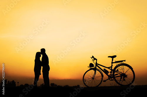 Silhouette of sweet couple in love happy time and bicycle in beautiful sunset