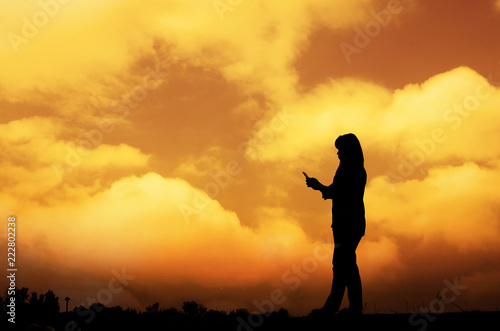 Silhouette woman on the phone with a sunset background