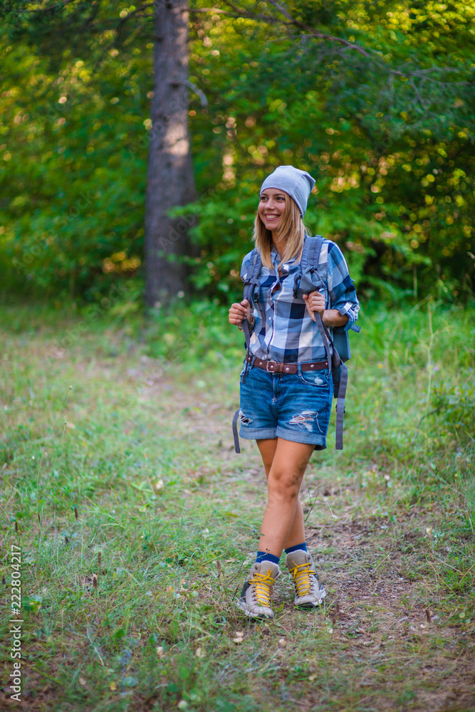 Young woman walking alone in the woods. Hiking concept in the mountain in summer Young woman walking alone in the woods. Hiking concept in the mountain in summer