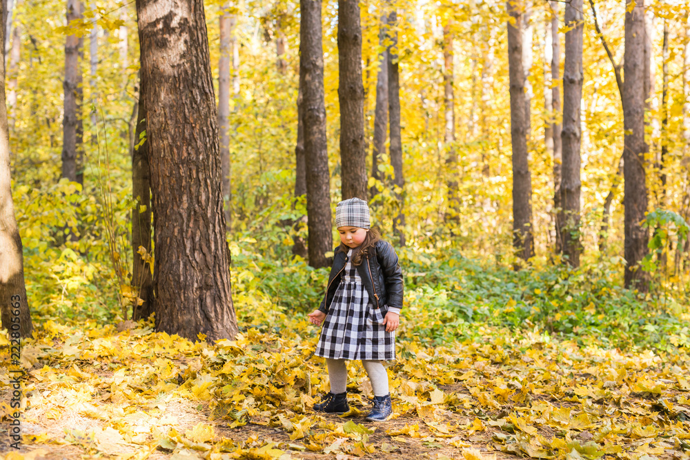 Childhood, fall, people concept - little girl walking in autumn leaves. Childhood, fall, people concept - little girl walking in autumn leaves.