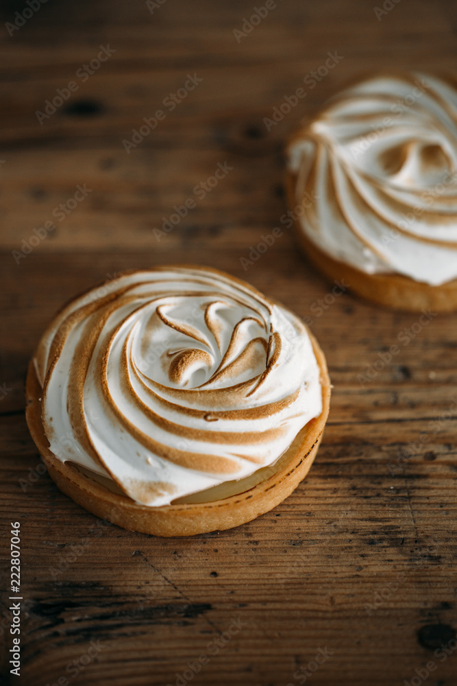 Tartlet with lemon cream and meringue on old rustic wooden background