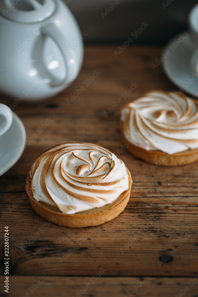 Tartlet with lemon cream and meringue on old rustic wooden background Tartlet with lemon cream and meringue on old rustic wooden background