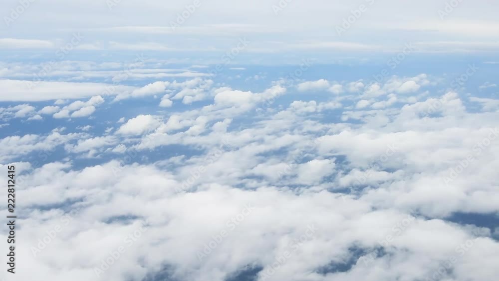 Aerial view of clouds and blue sky through airplane window Aerial view of clouds and blue sky through airplane window