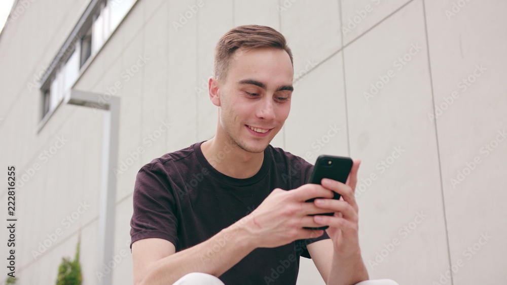 A young man using a phone in the city street. Close-up shot. Soft focus A young man using a phone in the city street. Close-up shot. Soft focus