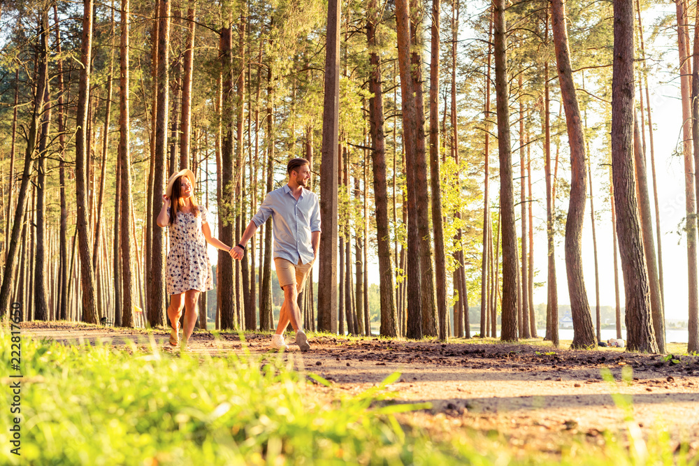 Fototapeta premium Young couple in love walking in the autumn park holding hands looking in the sunset.