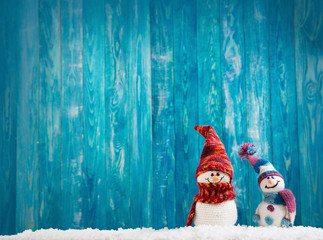 little knitted snowmans on soft snow on blue background