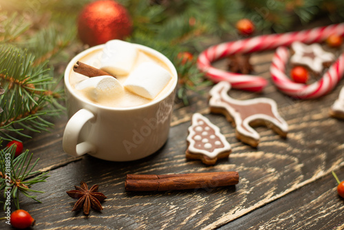 Winter warming sweet drink hot latte with marshmallows and cocoa in a mug with a Christmas holiday cinnamon on a wooden background, selective focus