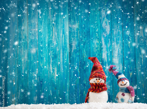 little knitted snowmans on soft snow on blue background photo