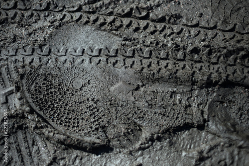 a printed footprint of a boot and a bicycle tire in the mud photo