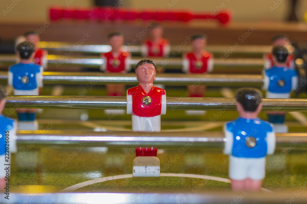 Red and white uniform table soccer player figurine on foosball board Red and white uniform table soccer player figurine on foosball board