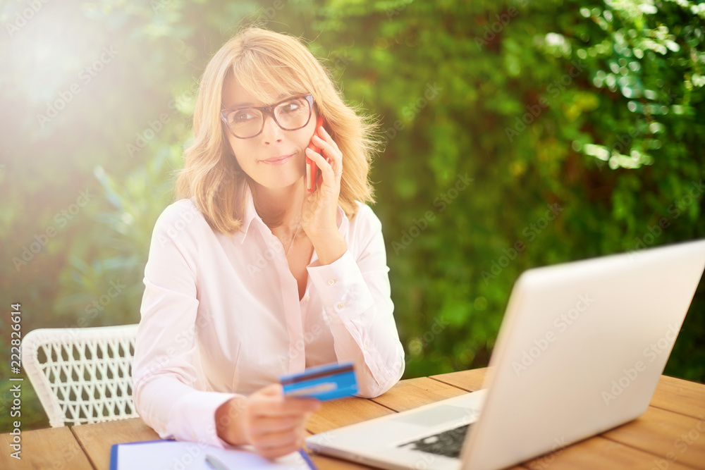 Woman using credit card and laptop at home outside on terrace. Outdoor portrait. Woman using credit card and laptop at home outside on terrace. Outdoor portrait.