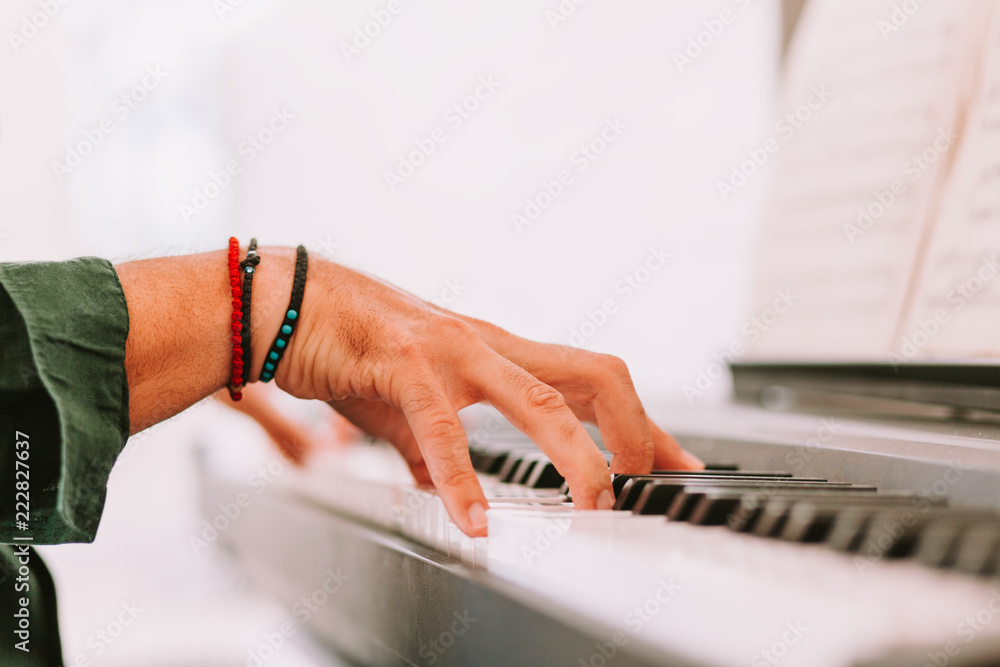 Male hands playing piano at home studio