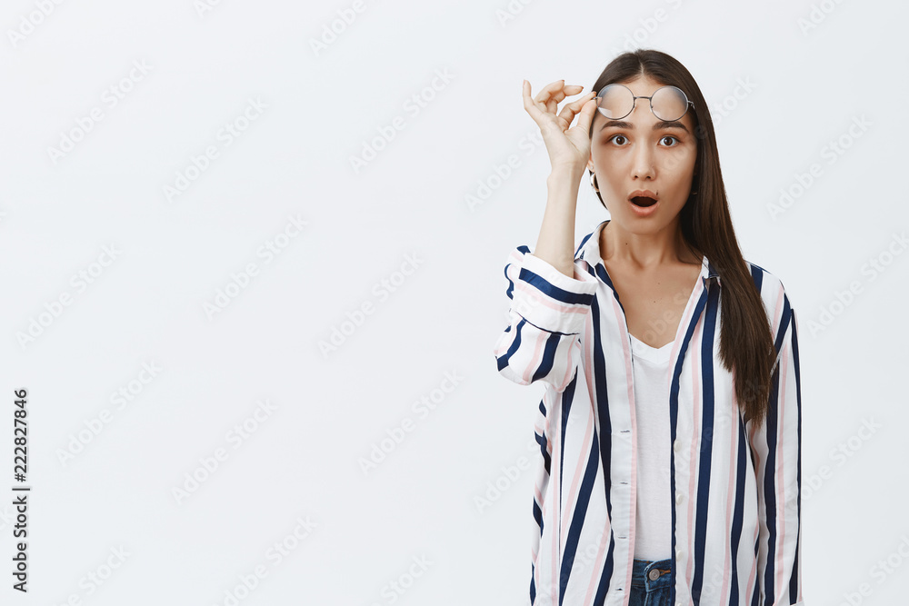 Gosh, no way. Portrait of shocked and thrilled good-looking stylish woman taking off glasses, gasping, dropping jaw while staring amazed at camera, standing excited over gray background Gosh, no way. Portrait of shocked and thrilled good-looking stylish woman taking off glasses, gasping, dropping jaw while staring amazed at camera, standing excited over gray background