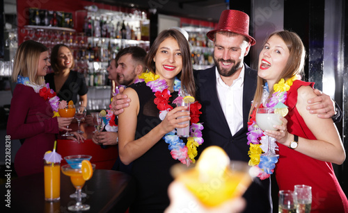 Man with female friends on Hawaiian party in bar