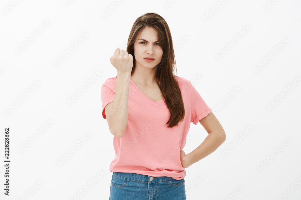 Do not underestimate women power. Angry annoyed urban female in casual clothes, holding hand on hip, frowning and gazing with pissed expression at camera while shaking fist in threaten gesture Do not underestimate women power. Angry annoyed urban female in casual clothes, holding hand on hip, frowning and gazing with pissed expression at camera while shaking fist in threaten gesture