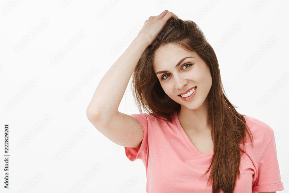 Portrait of charming woman with clean and beautiful skin, smiling and gently touching hair with hand, tilting head, enjoying great day in company of cute guy, flirting and looking feminine Portrait of charming woman with clean and beautiful skin, smiling and gently touching hair with hand, tilting head, enjoying great day in company of cute guy, flirting and looking feminine