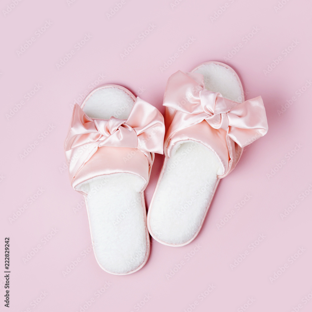 Stylid female slippers with bow on pale pink background. Flat lay, top view Stylid female slippers with bow on pale pink background. Flat lay, top view