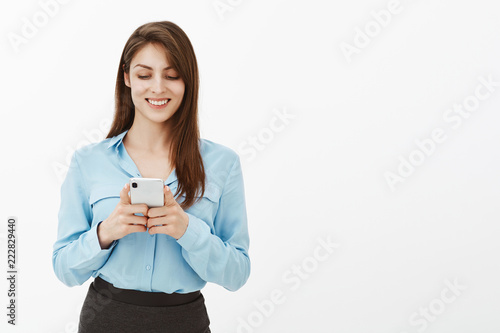 Wait sec, need send message to boyfriend. Attractive happy european female in blue blouse, playing app in bran new smartphone, gazing at screen while enjoying spending free time during lunch