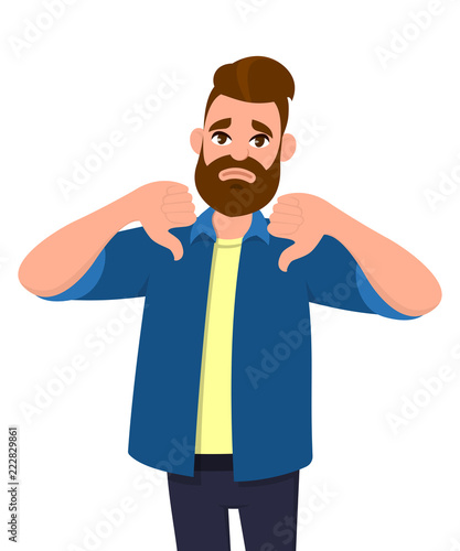 Unhappy young man showing thumbs down sign gesture. Dislike, disagree, disappointment, disapprove, no deal concept.