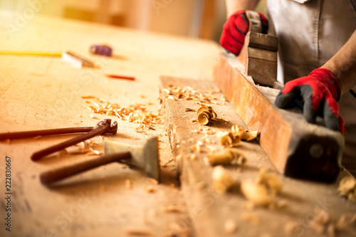 Carpenter working on woodworking machines in carpentry shop photo