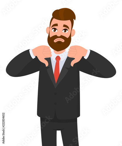 Young business man showing thumbs down sign, dislike, looks with negative expression and disapproval. Disagreement, disgust and negative expressions.