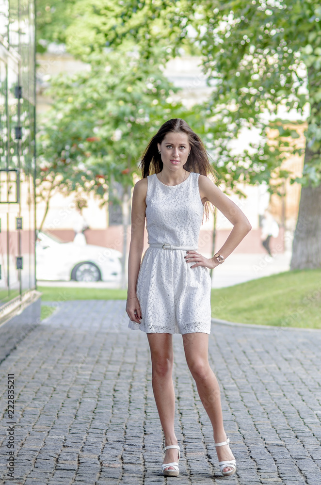 Beautiful young girl in a white summer dress near a showcase with reflection
Beautiful young girl in a white summer dress near a showcase with reflection