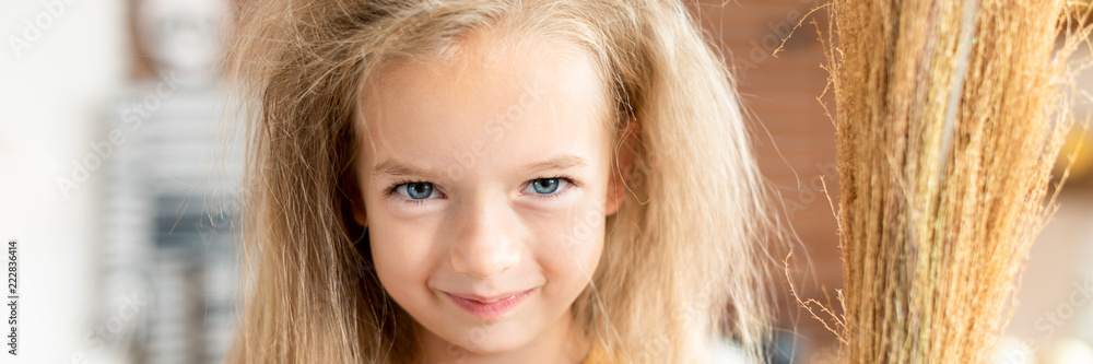 Cute little girl with messy hair, dressed up as a witch, holding a broom, looking at camera smiling. Halloween party or carnival costume banner. Cute little girl with messy hair, dressed up as a witch, holding a broom, looking at camera smiling. Halloween party or carnival costume banner.