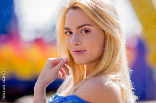 Portrait of a beautiful young woman with blond hair and a cute smile on a bright background