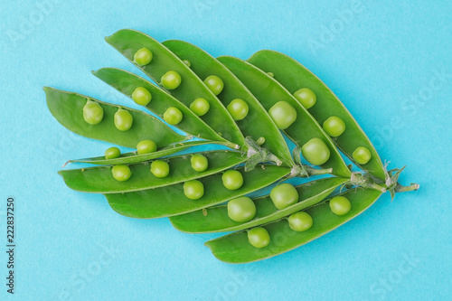 Green fresh peas lined in the form of a leaf in a stitch on a blue background. top view