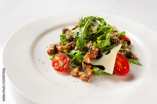 Plate with fried chicken meat served with salad, tomato, parmesan and sauce isolated at white background.
