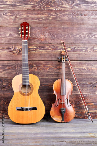 Guitar and violin on wooden background. Vintage style musical instruments on wooden surface, vertical image. Music still life. © DenisProduction.com